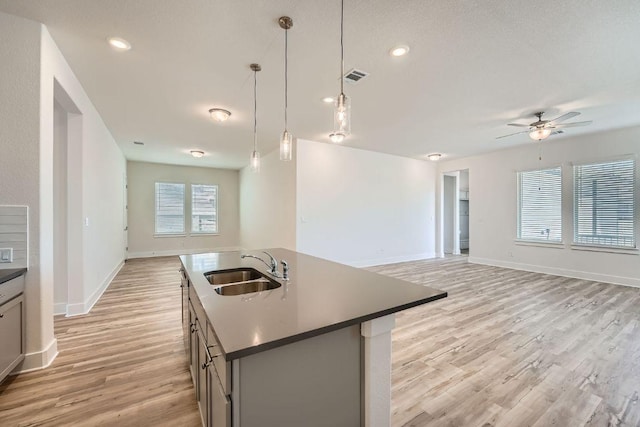 kitchen featuring a sink, a ceiling fan, light wood finished floors, open floor plan, and visible vents