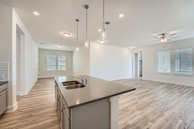 144 Adelton Blvd, Bastrop, TX 78602 - kitchen with a sink, light wood-style flooring, ceiling fan, open floor plan, and dark countertops