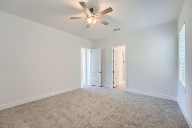 empty room featuring baseboards, ceiling fan, visible vents, and carpet