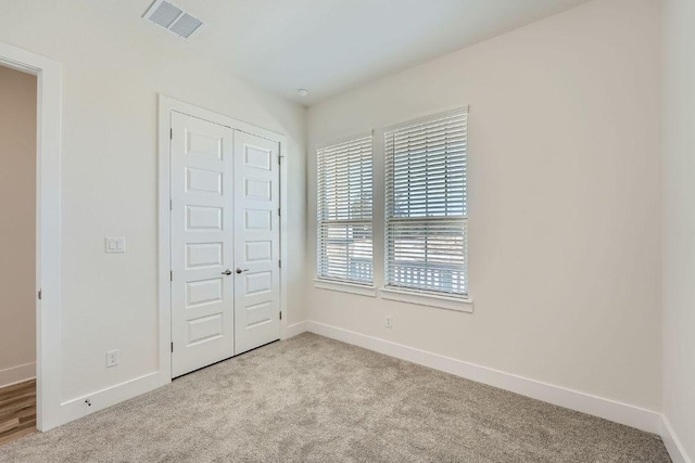 unfurnished bedroom featuring baseboards, visible vents, and light colored carpet