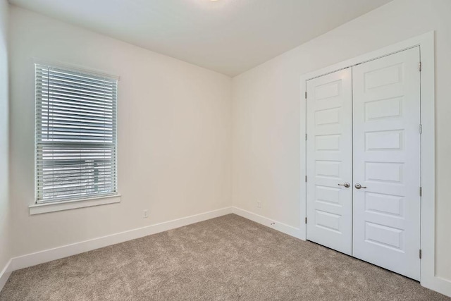 unfurnished bedroom featuring baseboards, carpet flooring, and a closet