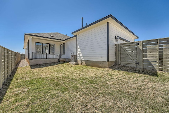 back of property with a lawn, a gate, and fence private yard