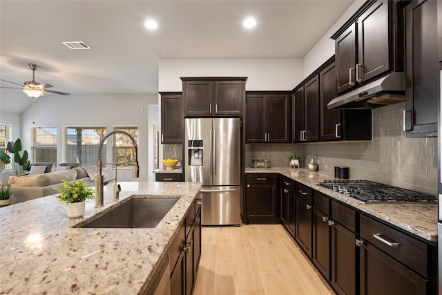 kitchen featuring dark brown cabinetry, sink, light stone counters, light hardwood / wood-style flooring, and appliances with stainless steel finishes