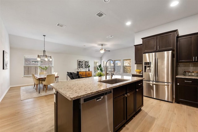 kitchen featuring sink, a center island with sink, appliances with stainless steel finishes, ceiling fan with notable chandelier, and light wood-type flooring