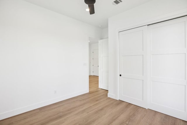 unfurnished bedroom featuring ceiling fan, light hardwood / wood-style floors, and a closet