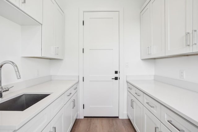 kitchen featuring wood-type flooring, white cabinetry, and sink