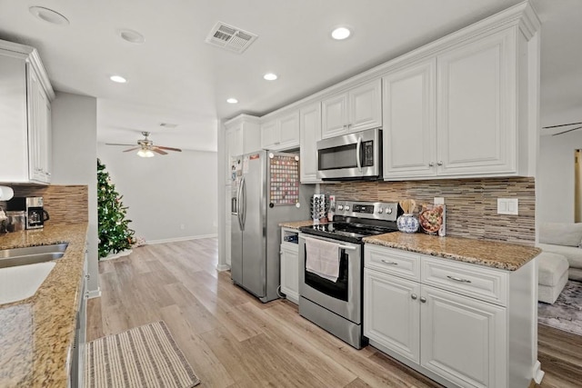 kitchen featuring visible vents, backsplash, light wood-style floors, appliances with stainless steel finishes, and white cabinets