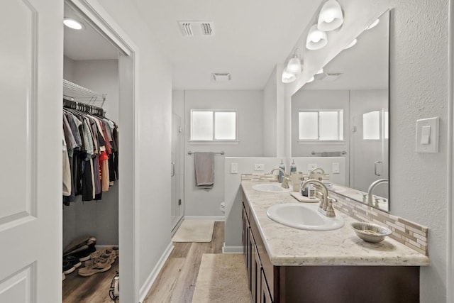 full bath with a sink, visible vents, and wood finished floors