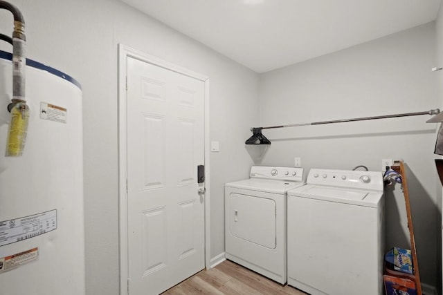 clothes washing area with washer and clothes dryer, laundry area, water heater, and light wood-style floors