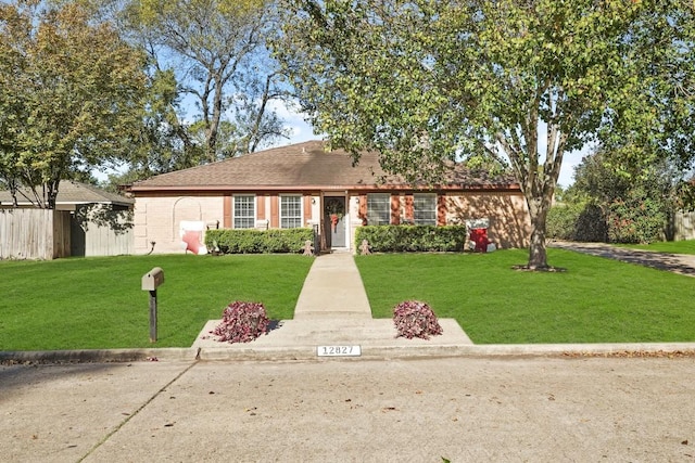 ranch-style house featuring brick siding, a front yard, and fence