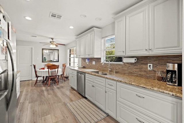 kitchen featuring tasteful backsplash, visible vents, stainless steel appliances, white cabinetry, and a sink