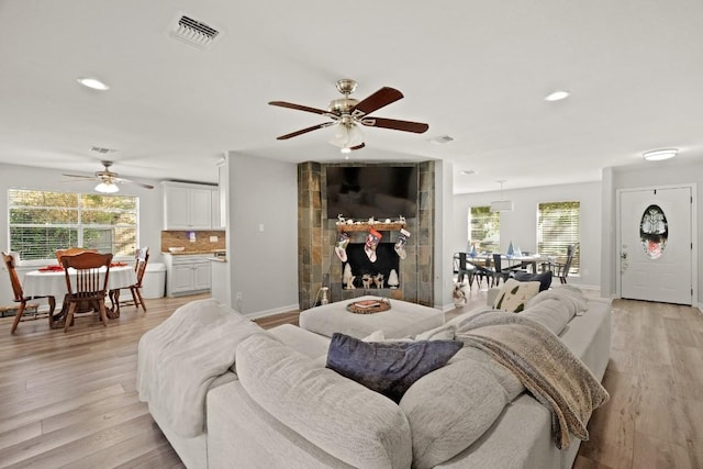 living room featuring light wood-style flooring, baseboards, visible vents, and a wealth of natural light