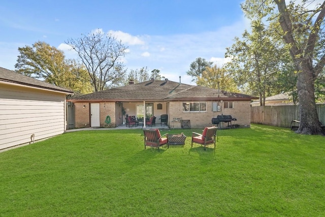 rear view of house with a yard, brick siding, and fence