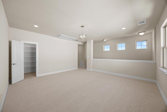 unfurnished room featuring a chandelier and light colored carpet