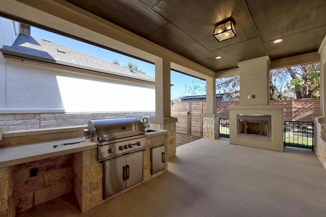 view of patio / terrace featuring exterior kitchen, an outdoor fireplace, a grill, and sink