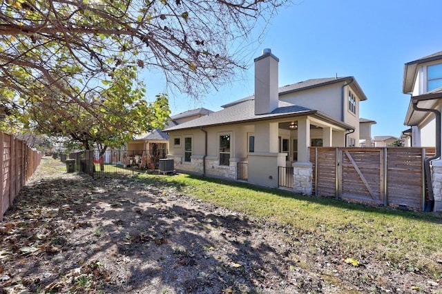 back of property with central AC and a yard