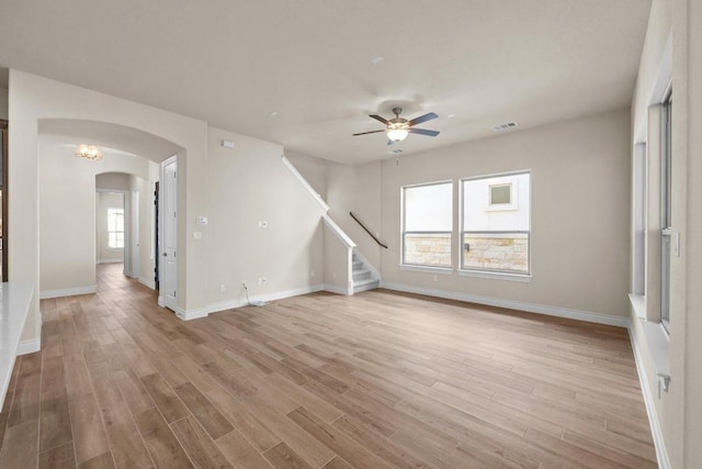 225 Skyflower Dr, Georgetown, TX 78628 - unfurnished living room featuring arched walkways, wood finished floors, ceiling fan, and stairway