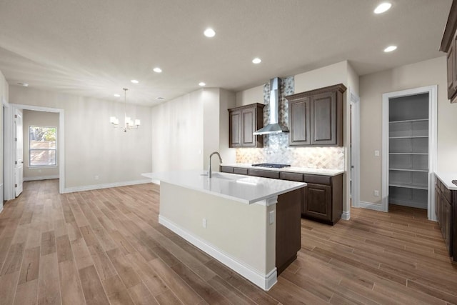 225 Skyflower Dr, Georgetown, TX 78628 - kitchen featuring wall chimney range hood, a sink, stainless steel gas stovetop, a chandelier, and light countertops