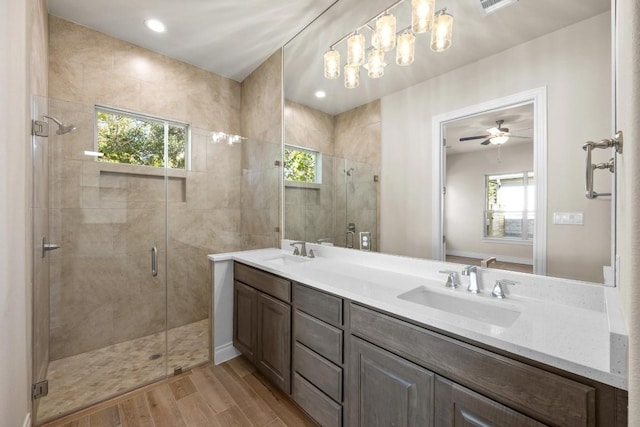 bathroom with ceiling fan with notable chandelier, vanity, wood-type flooring, and an enclosed shower