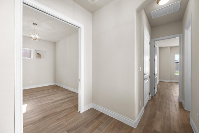 225 Skyflower Dr, Georgetown, TX 78628 - hallway with wood finished floors, baseboards, and a chandelier
