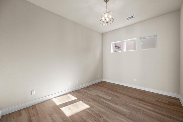 spare room featuring hardwood / wood-style floors and a notable chandelier