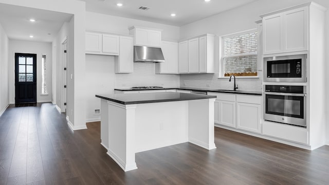 113 Golden Sage Ave, Georgetown, TX 78633 - kitchen with stainless steel oven, ventilation hood, dark countertops, built in microwave, and dark wood-type flooring