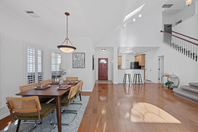 dining space featuring light wood-type flooring, baseboards, stairs, and visible vents