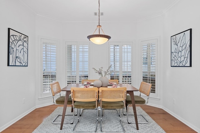 dining space featuring visible vents, crown molding, baseboards, and wood finished floors