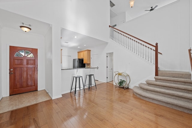 entrance foyer with visible vents, crown molding, light wood finished floors, and stairs