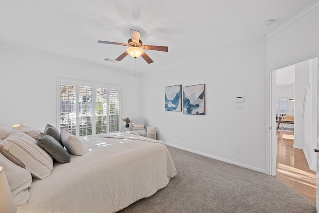 bedroom with carpet floors, a ceiling fan, visible vents, baseboards, and ornamental molding