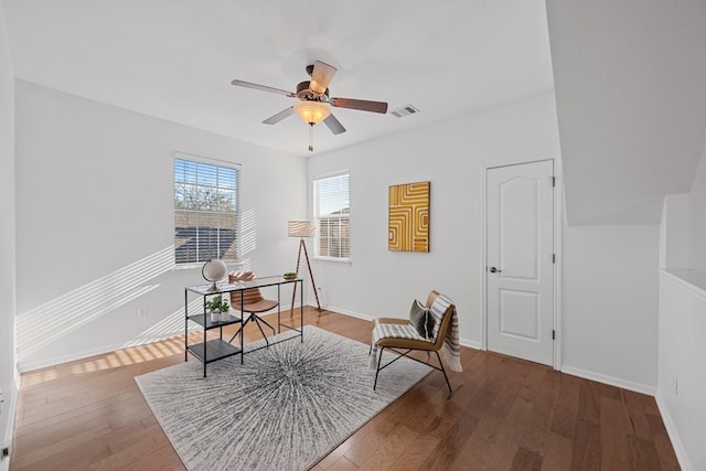 living area featuring visible vents, wood finished floors, a ceiling fan, and baseboards