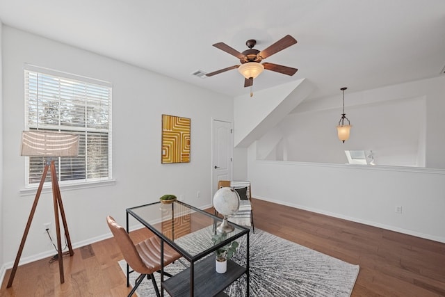 home office with a ceiling fan, baseboards, visible vents, and wood finished floors