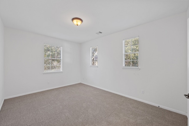 unfurnished room with carpet flooring, visible vents, and baseboards