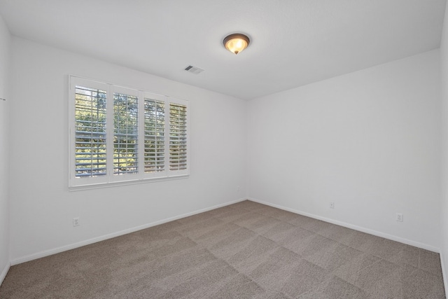 carpeted spare room with visible vents and baseboards