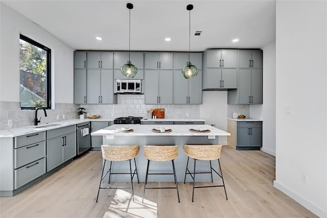 kitchen with a kitchen island, light hardwood / wood-style floors, sink, and appliances with stainless steel finishes