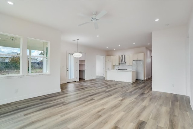 189 Mauna Kea Ln, Bastrop, TX 78602 - unfurnished living room with light wood-style flooring, a ceiling fan, recessed lighting, baseboards, and a sink