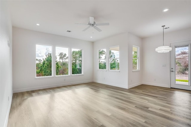 empty room featuring light wood-type flooring, plenty of natural light, and ceiling fan