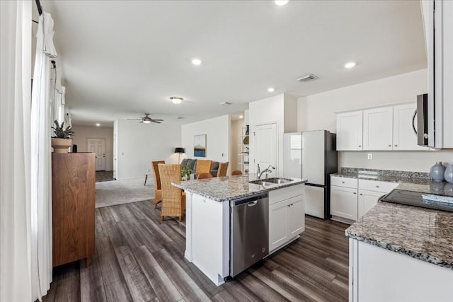 kitchen with dark hardwood / wood-style flooring, stainless steel appliances, white cabinetry, and an island with sink