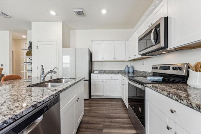 kitchen with light stone countertops, sink, dark wood-type flooring, stainless steel appliances, and white cabinets