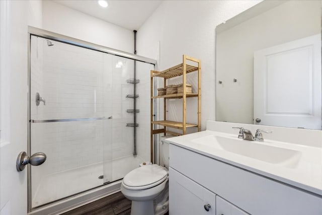 bathroom with toilet, vanity, an enclosed shower, and hardwood / wood-style flooring