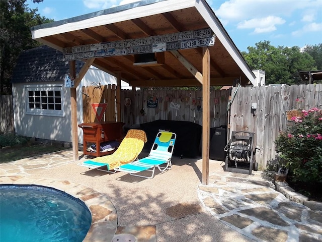 view of patio with fence, a fenced in pool, and an outbuilding