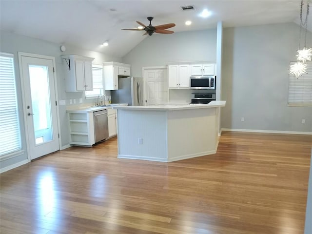 kitchen with hanging light fixtures, appliances with stainless steel finishes, white cabinets, and a kitchen island