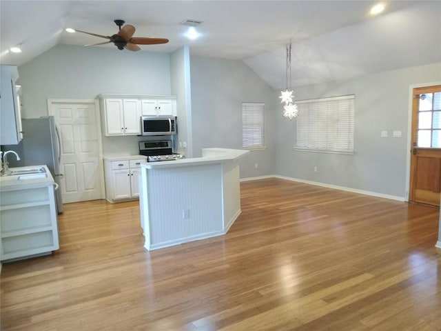 kitchen with range, decorative light fixtures, white cabinetry, sink, and vaulted ceiling