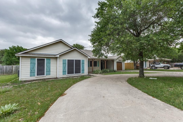 single story home featuring fence, curved driveway, and a front lawn