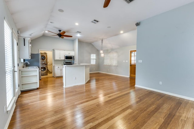 unfurnished living room with vaulted ceiling, ceiling fan with notable chandelier, and visible vents