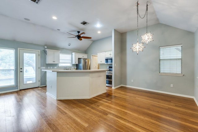 kitchen with white cabinets, visible vents, light wood-style floors, stainless steel appliances, and vaulted ceiling