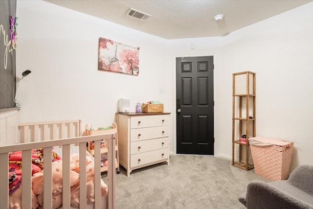 carpeted bedroom with a textured ceiling and a crib