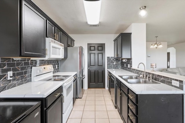 kitchen with white appliances, sink, light tile patterned floors, decorative light fixtures, and a chandelier