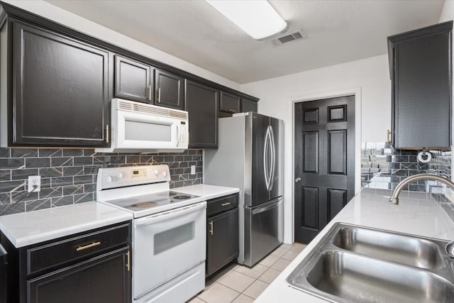 kitchen with white appliances, sink, light tile patterned floors, and tasteful backsplash