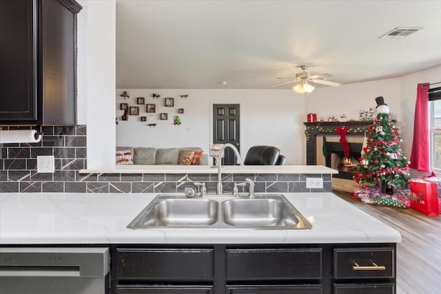 kitchen with decorative backsplash, dishwashing machine, ceiling fan, sink, and light hardwood / wood-style flooring